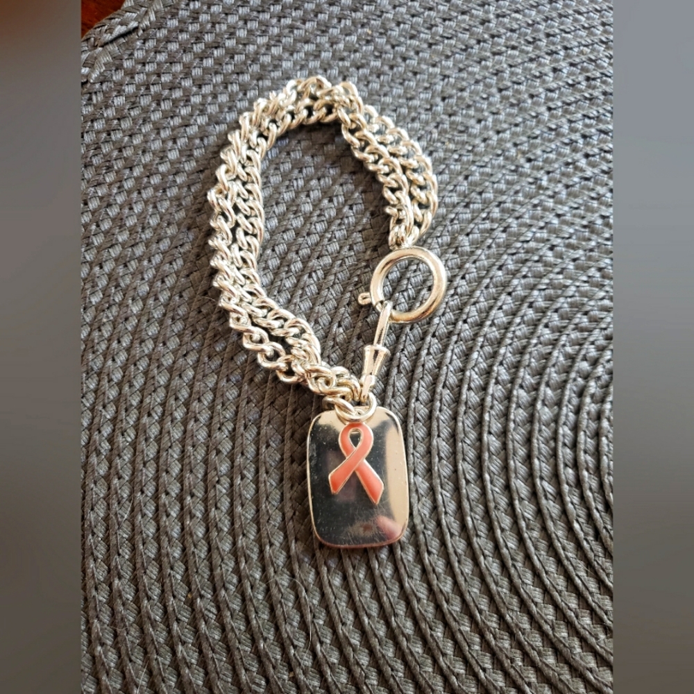 Breast cancer support stainless steel charm bracelet with pink ribbon.